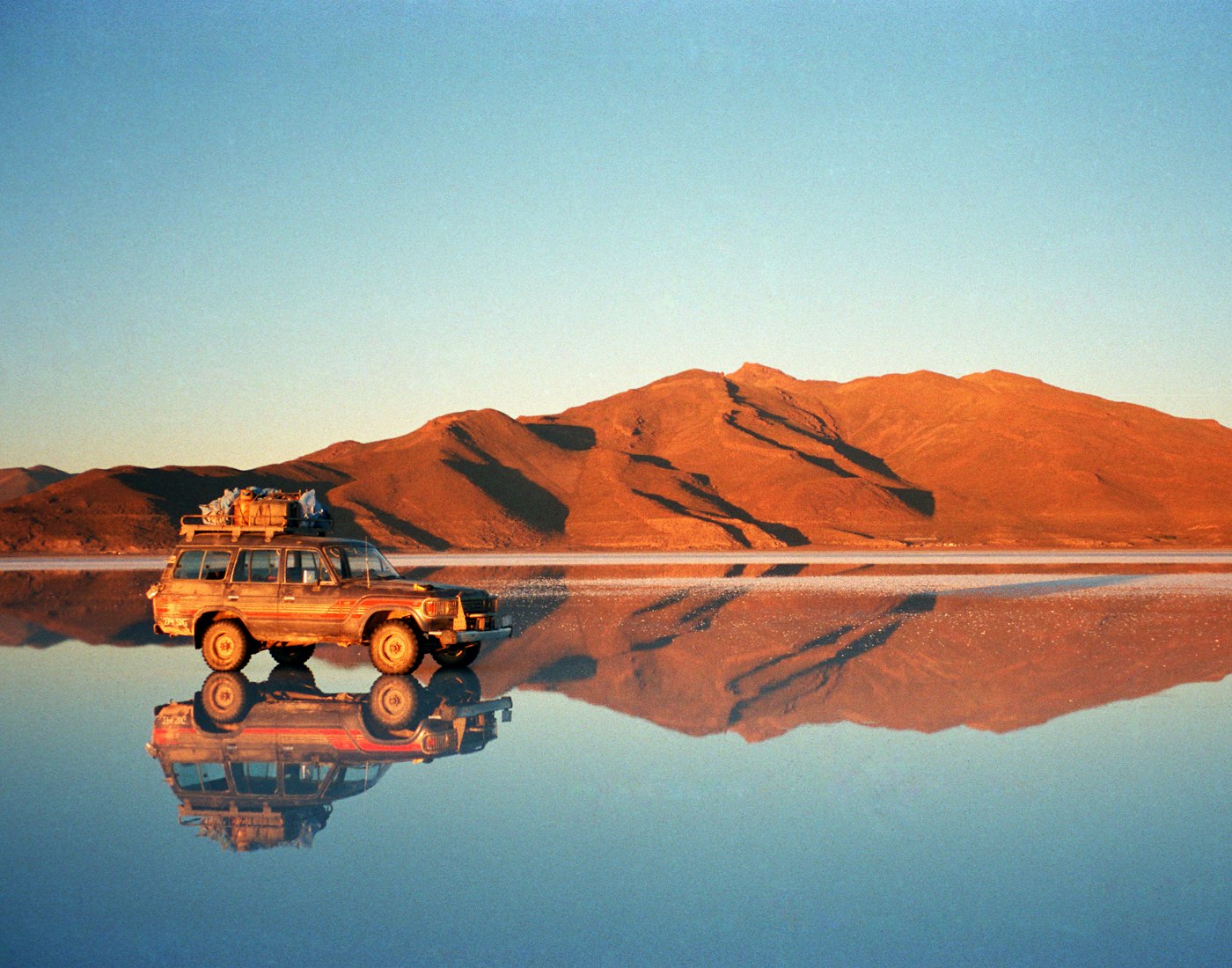 The vast, mirror-like expanse of the Salar de Uyuni salt flats under a dramatic sky