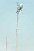 man in blue suit on top of the electic post