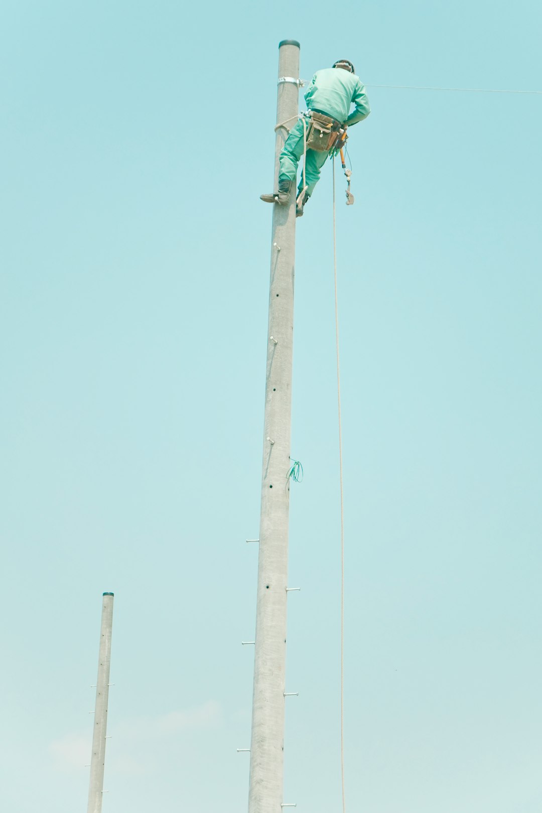 man in blue suit on top of the electic post