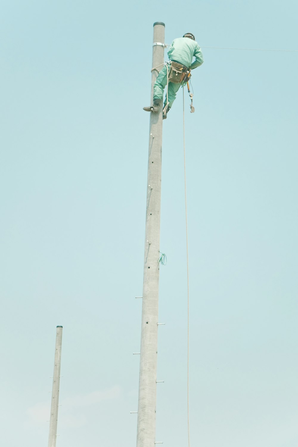 man in blue suit on top of the electic post