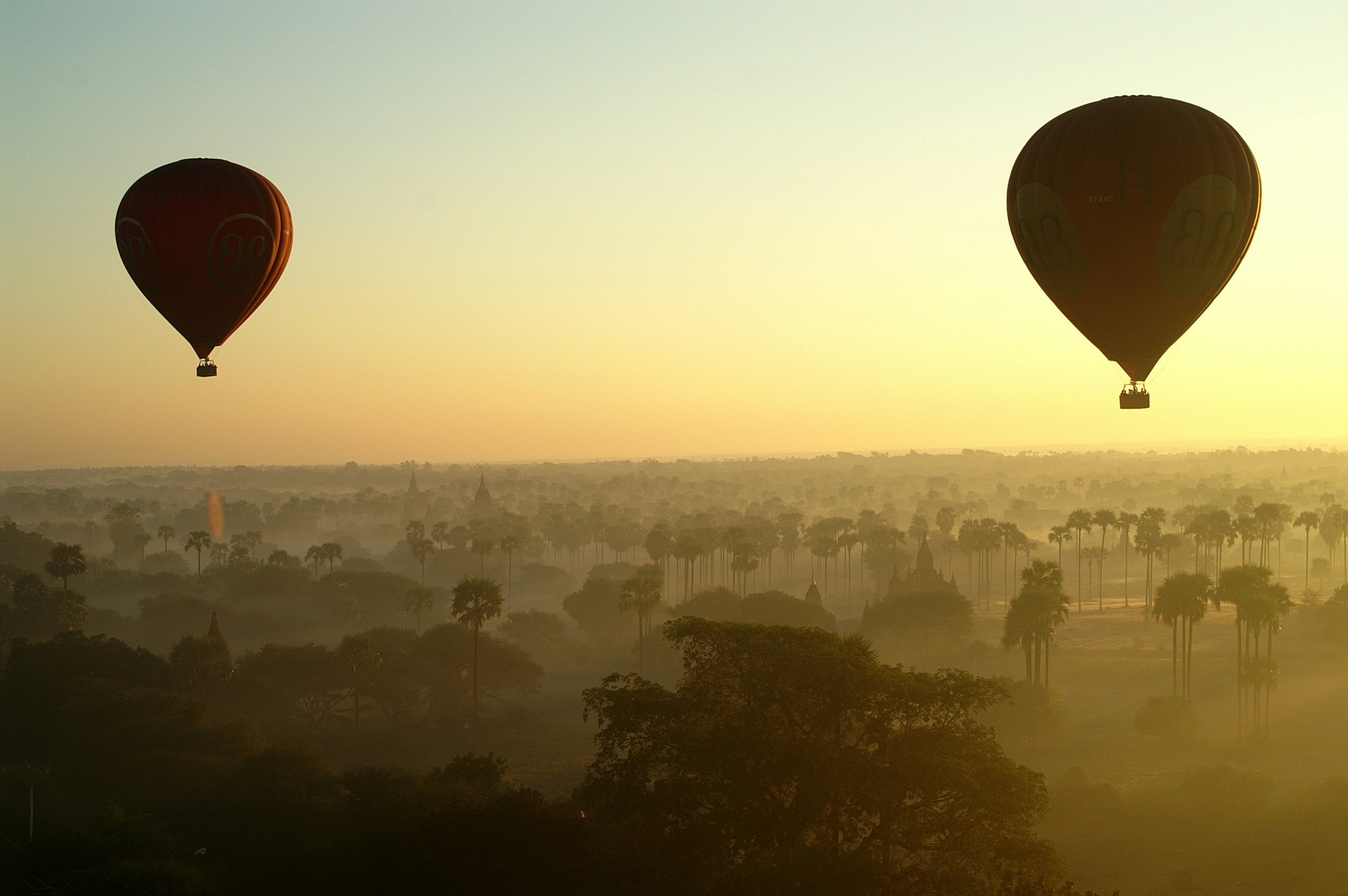 Two hot air balloons rising together into the sky over Bagan