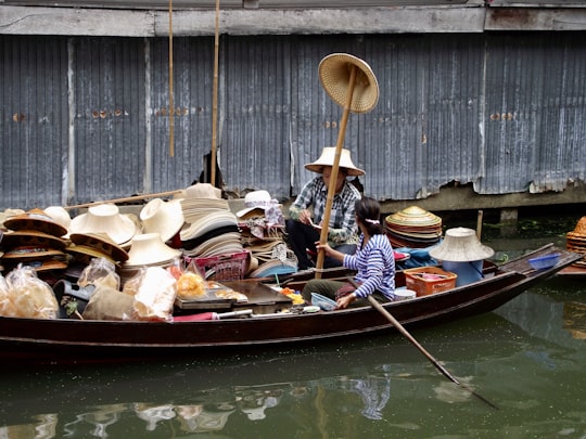 two women on boat beside hat lot in Khlong Hae Floating Market Thailand