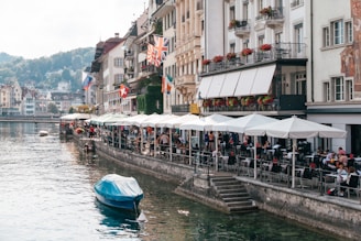 A happy traveler enjoying a riverside café in London, with historic buildings in the background.