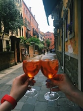 A cheerful couple clinking colorful cocktails on a cruise ship deck at sunset.