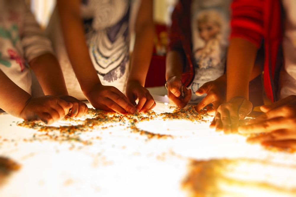 a group of children standing around a white table