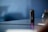 A compact, cylindrical camera with multiple LED indicators stands upright on a reflective surface. The background is softly blurred, creating a sense of focus on the camera, which has a sleek, modern design.