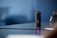 A compact, cylindrical camera with multiple LED indicators stands upright on a reflective surface. The background is softly blurred, creating a sense of focus on the camera, which has a sleek, modern design.