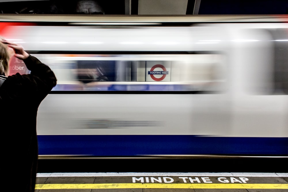 person standing on train station front of passing train