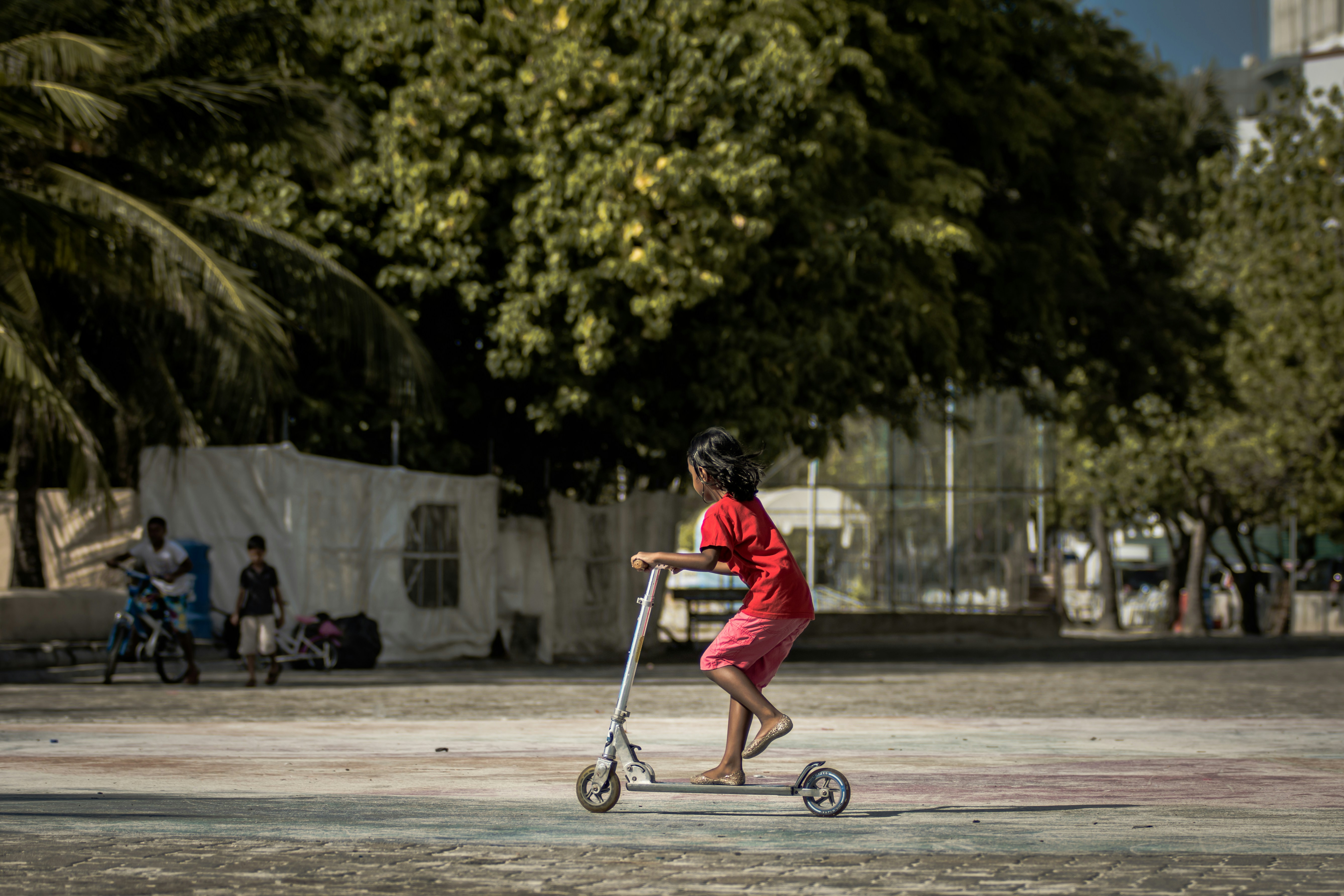 girl riding kick scooter during daytime