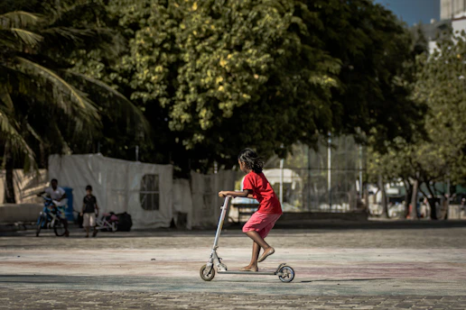 A student practicing scooter riding on a quiet Koramangala street under instructor supervision.