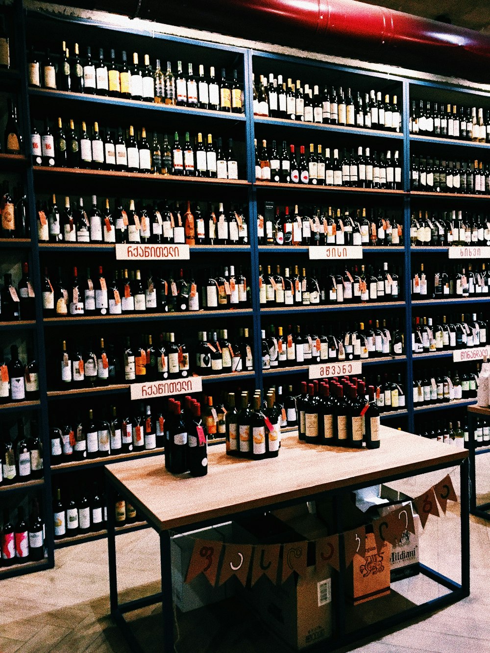 lotto di bottiglie di vino con etichette assortite su tavolo e scaffali