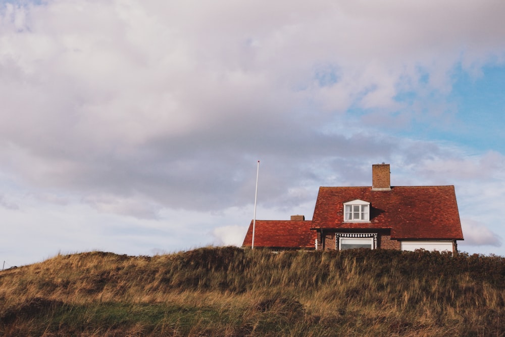 grey clouds hovering above house on top of hill