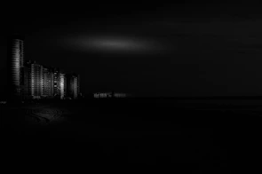 Night scene of Avenida Atlântica with illuminated buildings reflecting on the ocean.