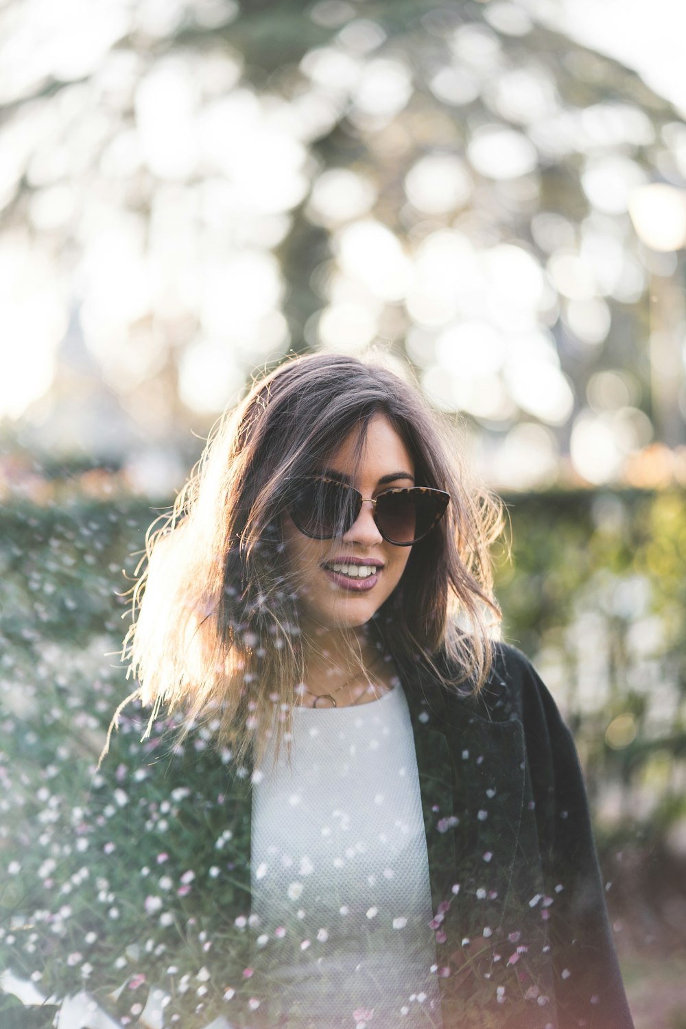 a woman wearing sunglasses standing in front of a tree