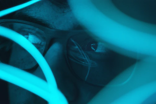 A close-up of a character's face with cybernetic implants glowing softly.