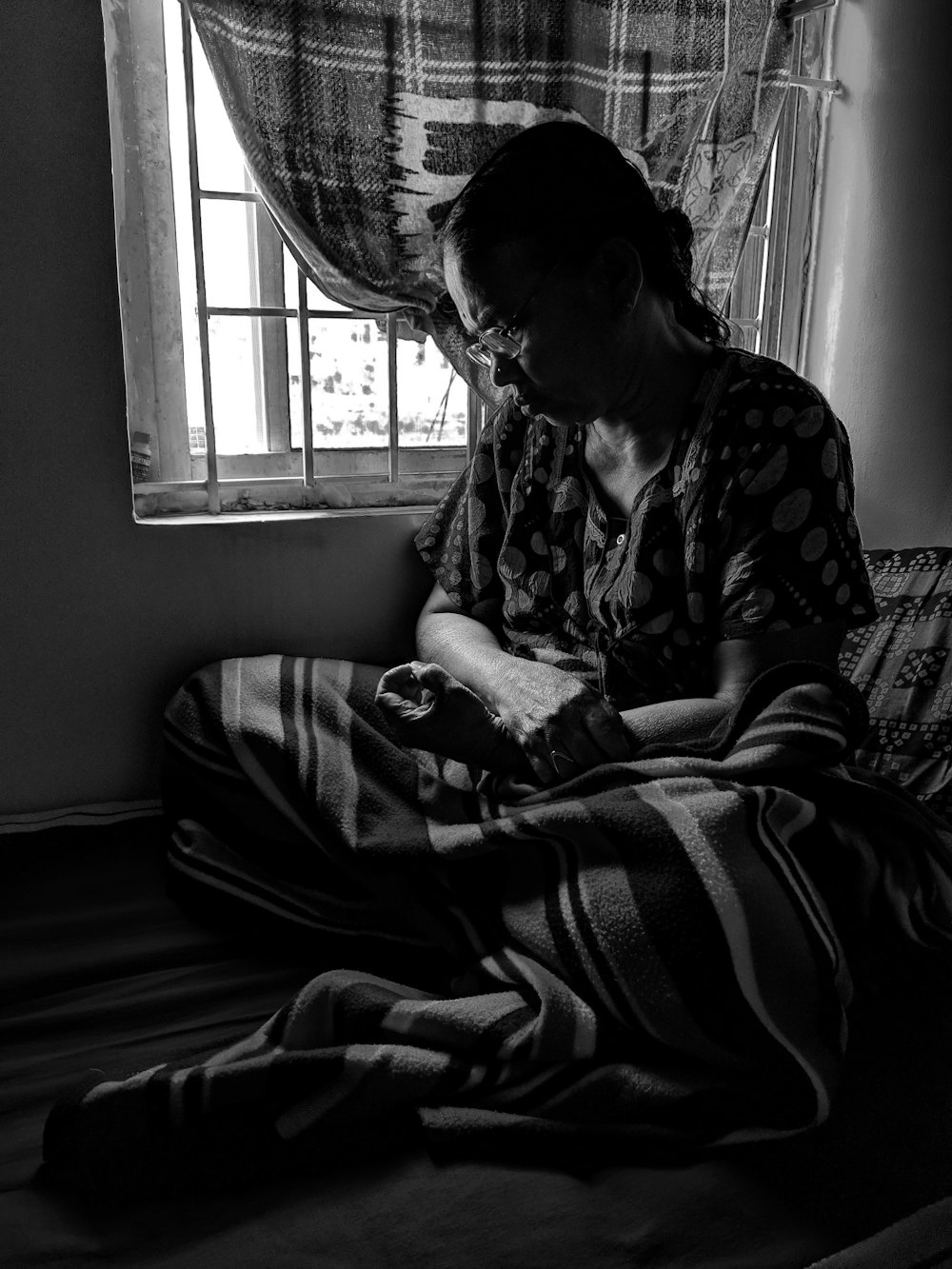 grayscale photo of woman sitting near window