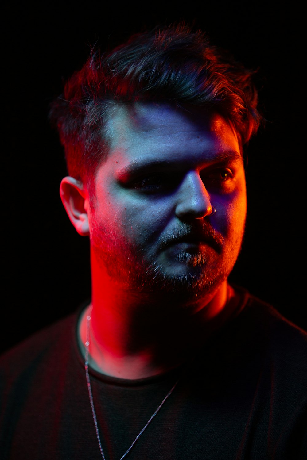 man wearing black crew-neck shirt and necklace