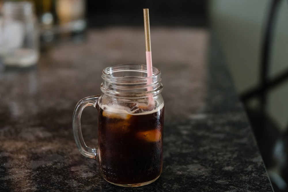Clear Glass Mason Jar Filled With Black Liquid On Gray Granite