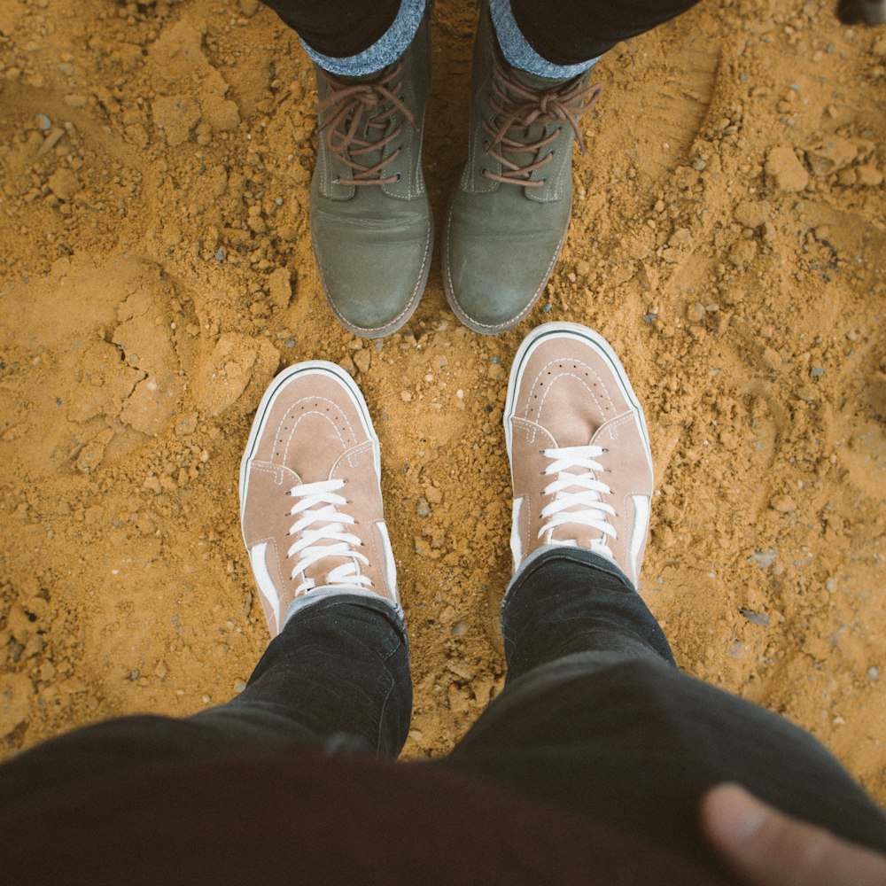 two person standing while facing sneakers