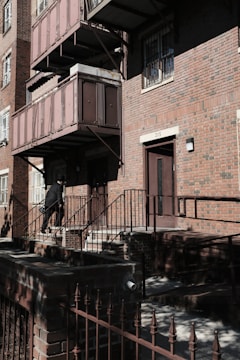A locksmith carrying equipment walking quickly towards a residential building.