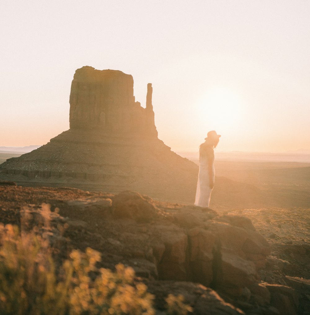 woman in white dress standing on rocky mountain