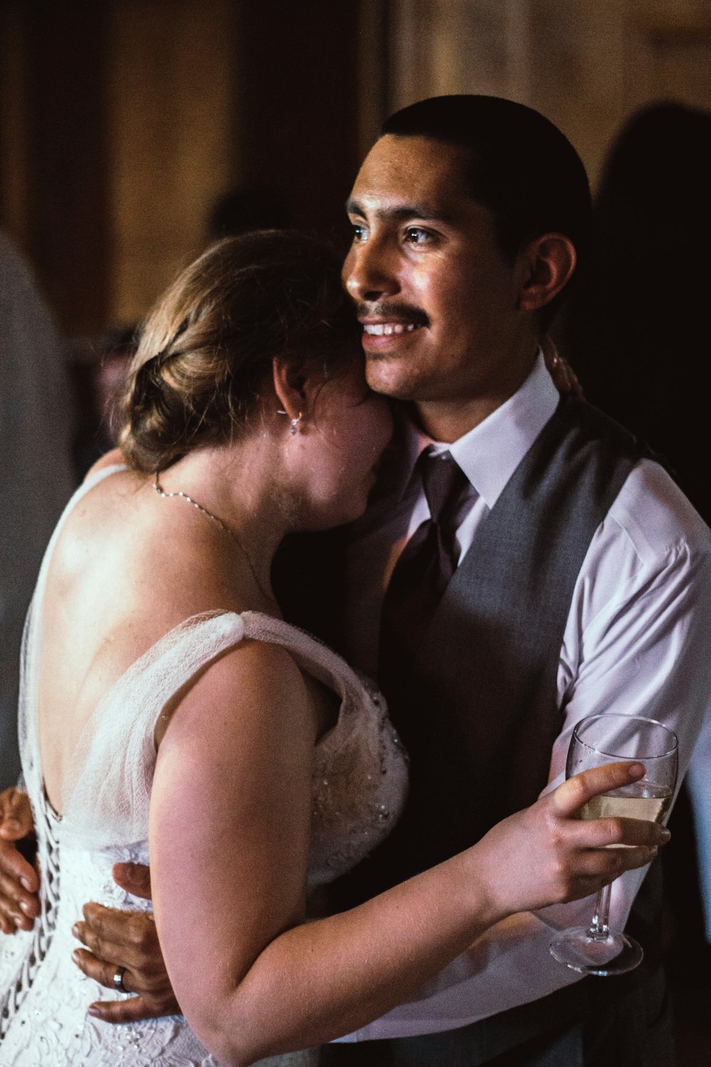 woman in white gown leaning face on man's shoulder