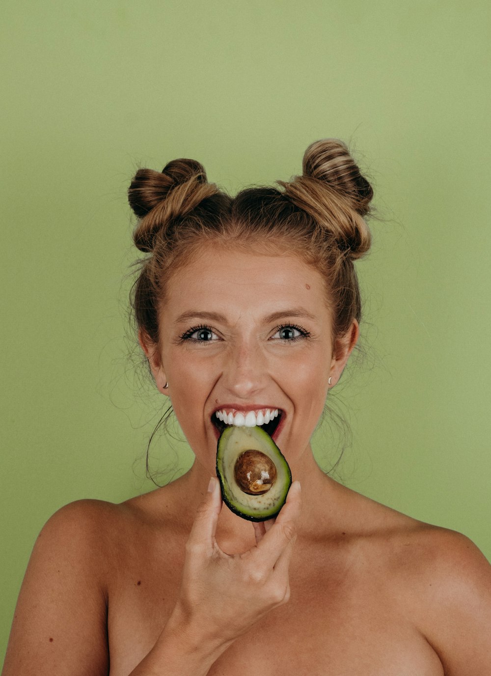 woman holding sliced avocado