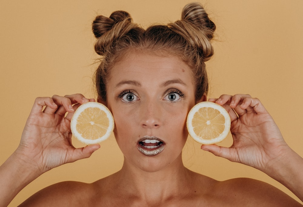 Mujer sosteniendo dos rodajas de limones