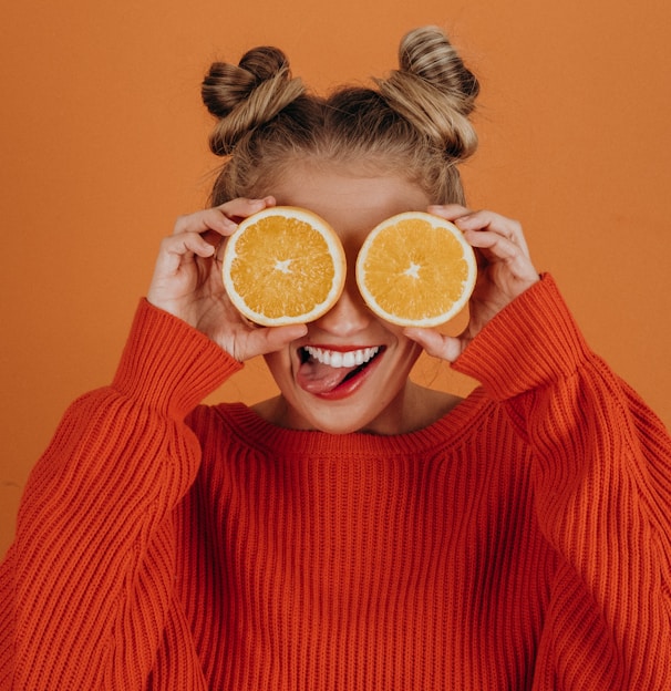 woman in red knit sweater holding lemon