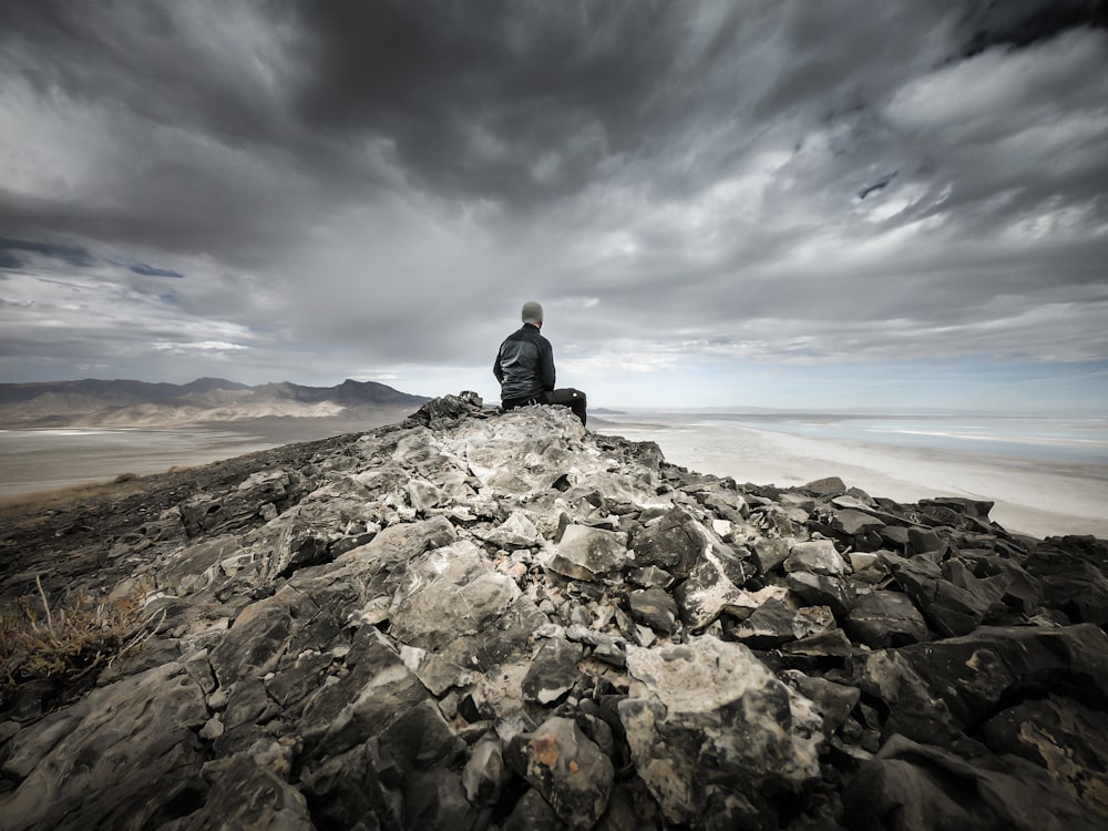 homme assis sur la montagne rocheuse grise