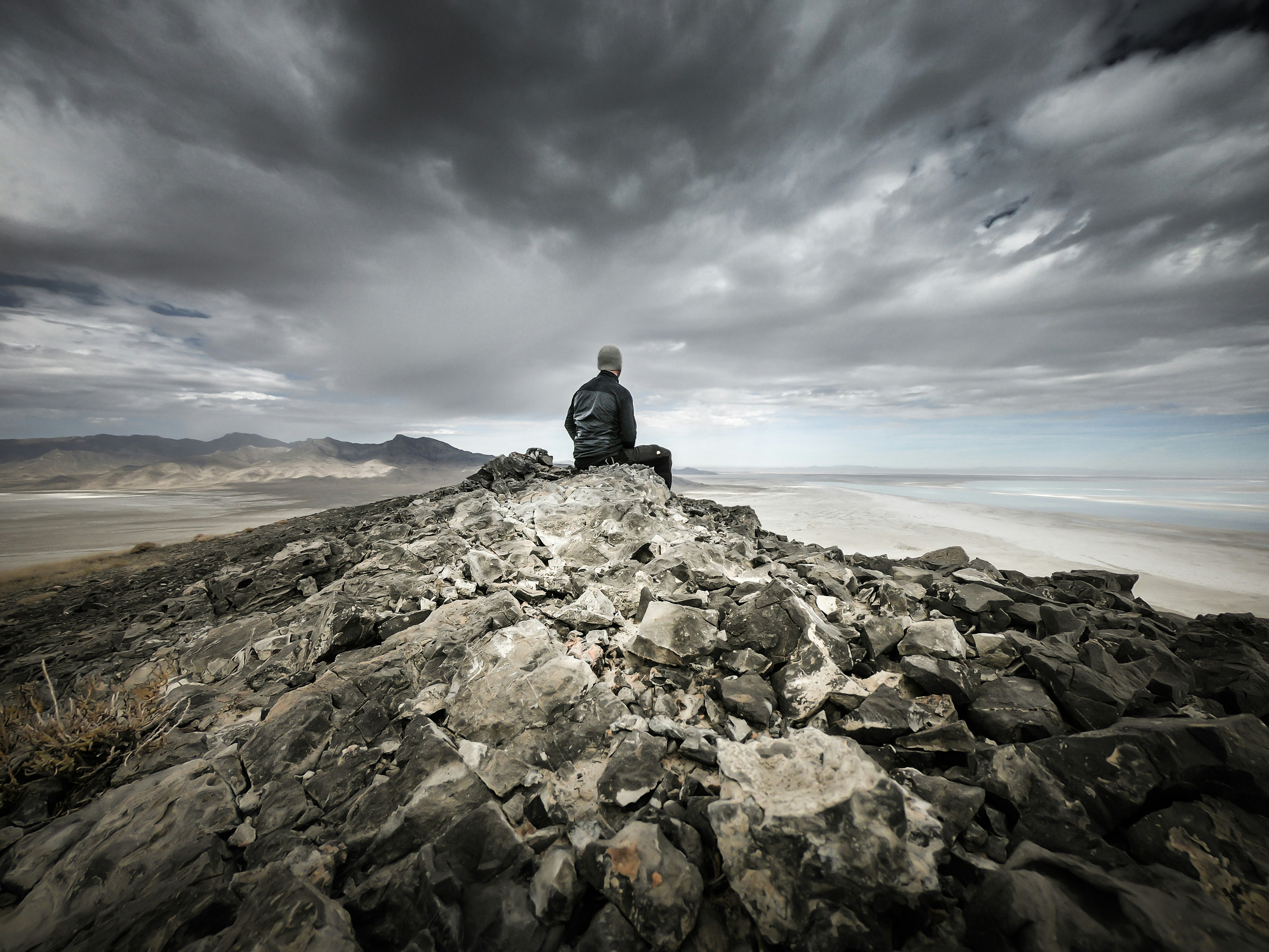 man siting on gray rocky mountain