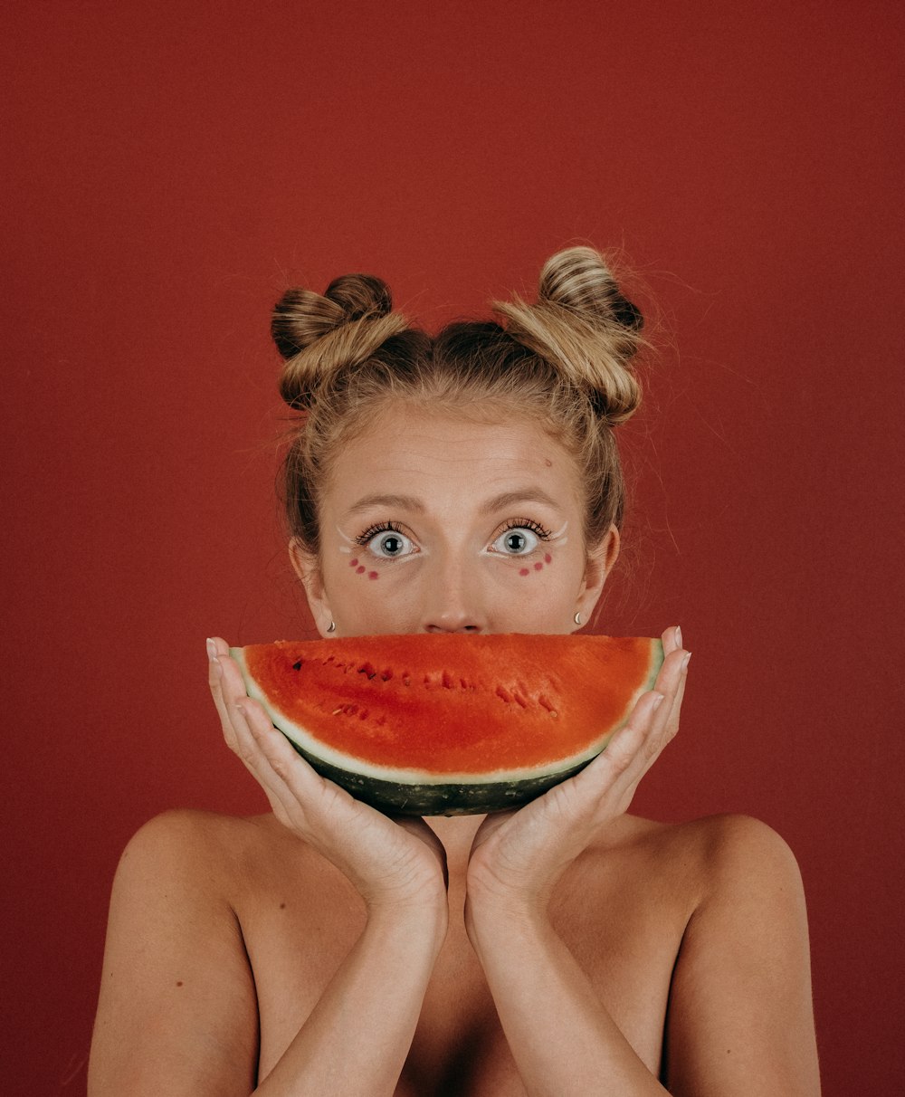 mulher cobrindo a boca com melancia