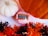 A pink colored bath bomb labeled 'Antidote Stress/Anxiety Bath Bomb' with a 'Pumpkin Spice' tag is placed between a white and an orange pumpkin. Surrounding these items is decorative shredded paper in black and orange colors, creating a festive atmosphere.