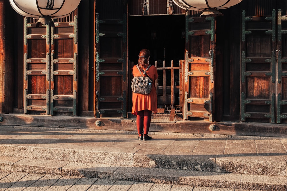 Mujer parada frente a la puerta del edificio durante el día