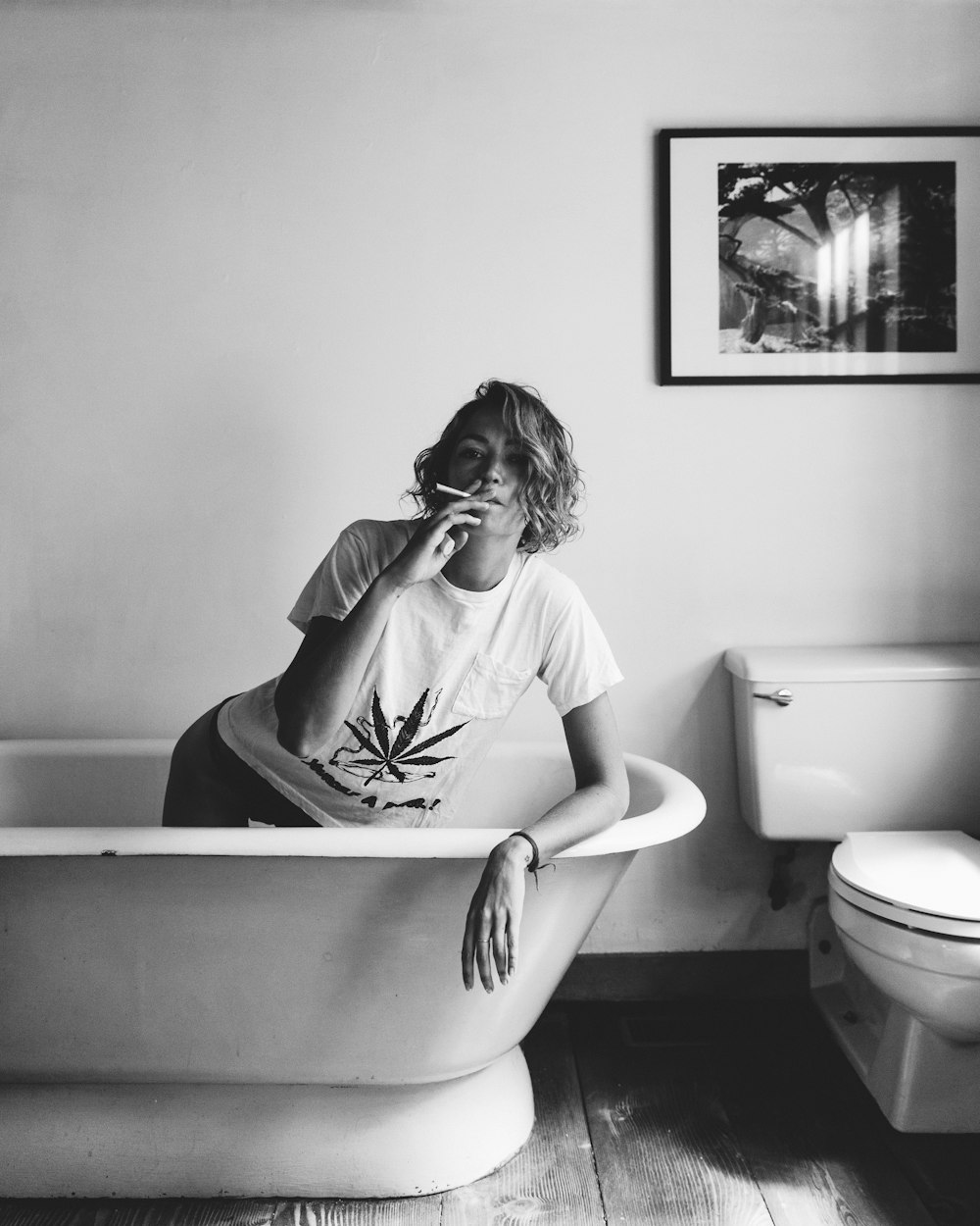 escala de grises de mujer fumando dentro de la bañera