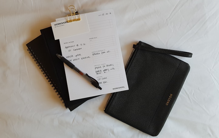 a notepad, pen, and notebook on a bed