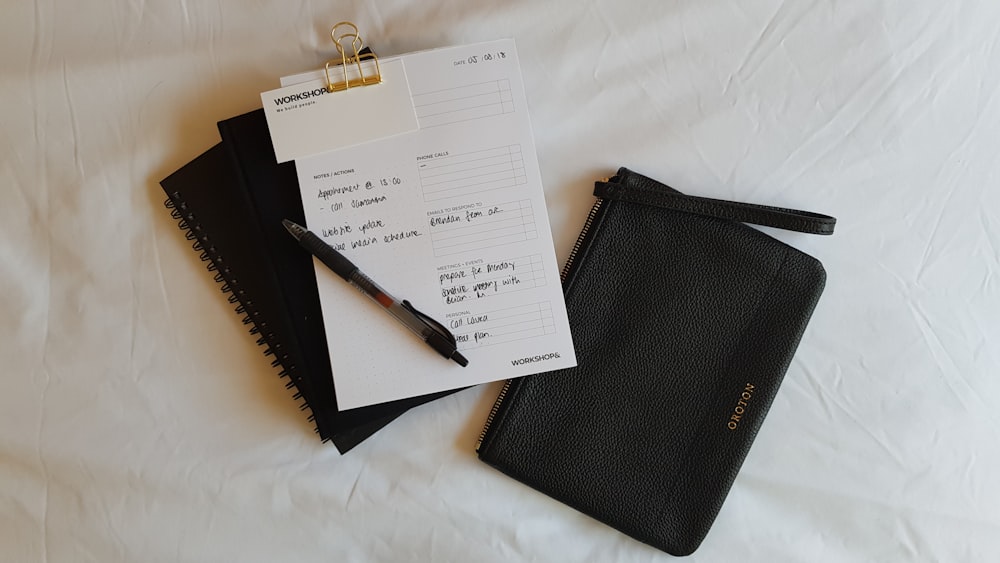 un bloc de notas, un bolígrafo y un cuaderno en una cama