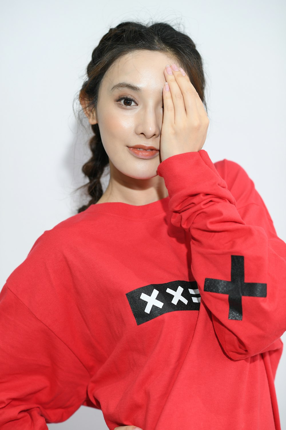 woman wearing red long-sleeved shirt standing beside wall