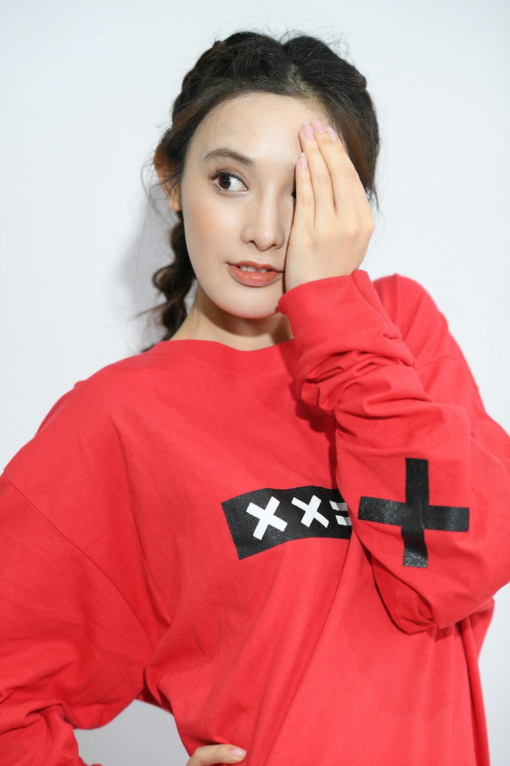 woman in red and black crew-neck sweater covering her left eye using her left hand