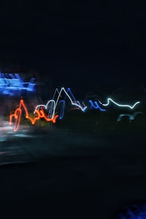 Bright, wavy lines of light in various colors are set against a dark background, creating an abstract and dynamic visual effect.