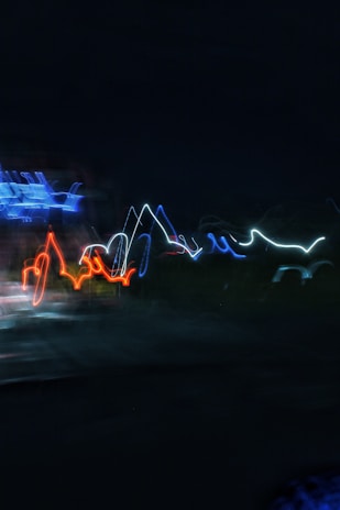 Bright, wavy lines of light in various colors are set against a dark background, creating an abstract and dynamic visual effect.
