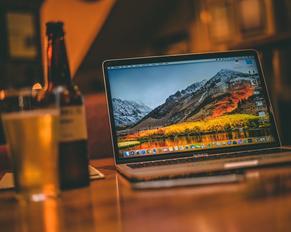 gray laptop beside glass bottle