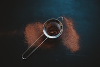 round grey metal filter with brown powder on black surface