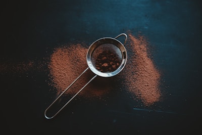 round grey metal filter with brown powder on black surface