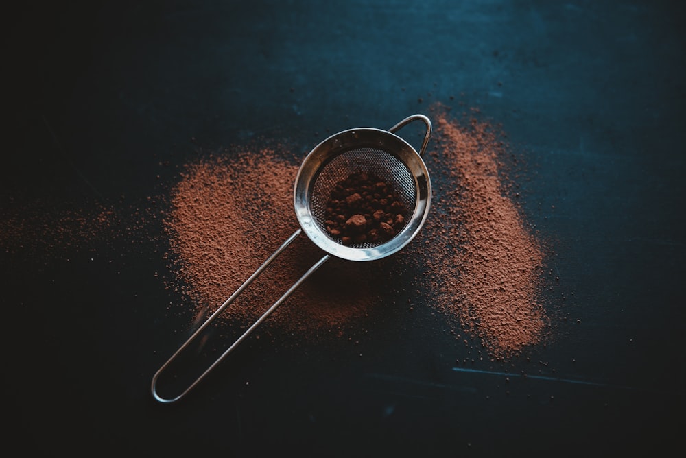 round grey metal filter with brown powder on black surface