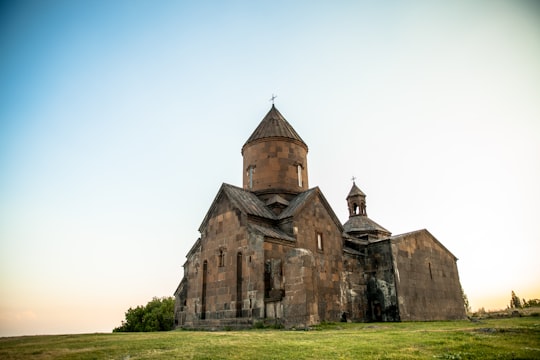 brown concrete church on green field at daytime in Saghmosavank Armenia