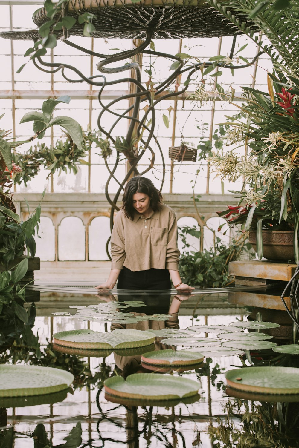 standing woman leaning on fountain with lily pads