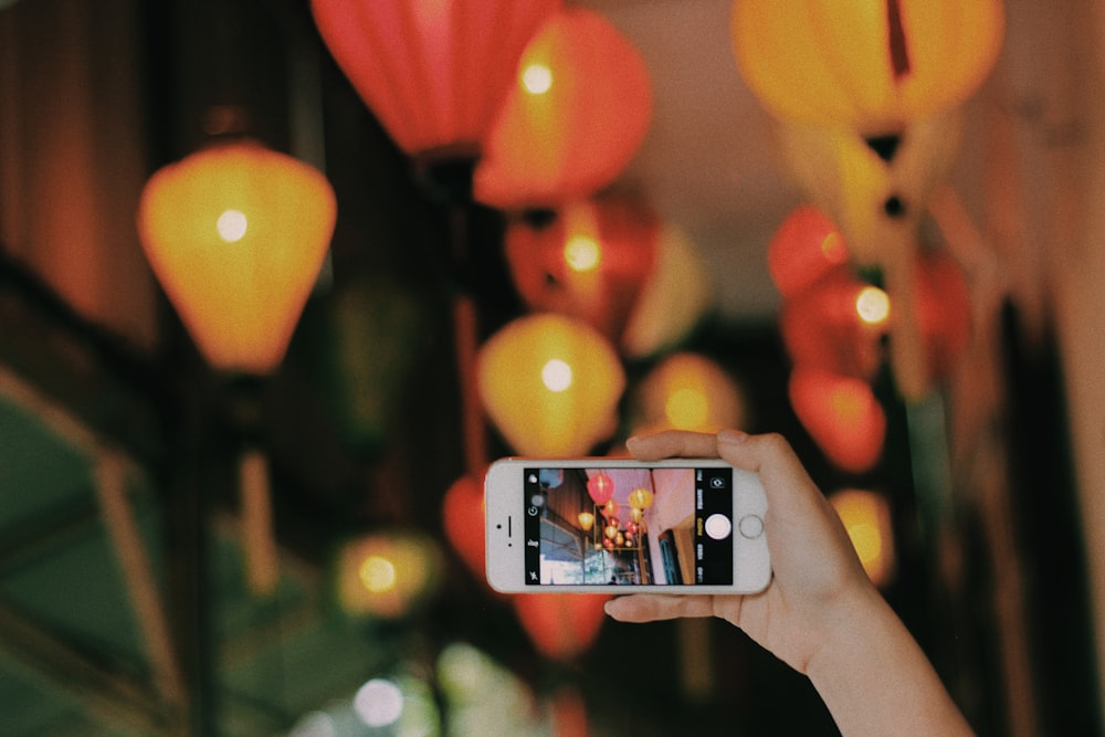 person taking photo of pendant lamps using iPhone