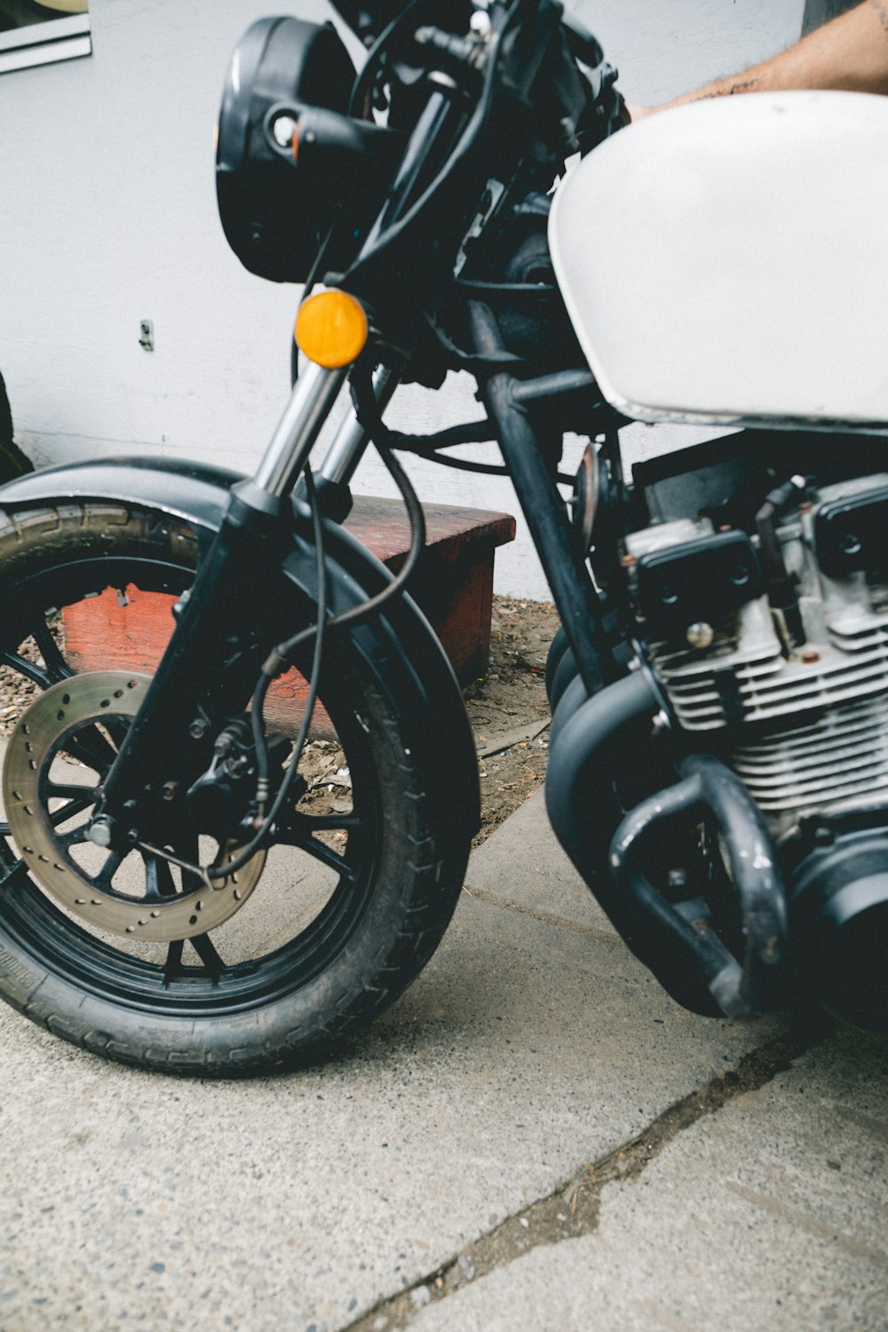 Motocicleta blanca y negra estacionada sobre superficie de concreto gris