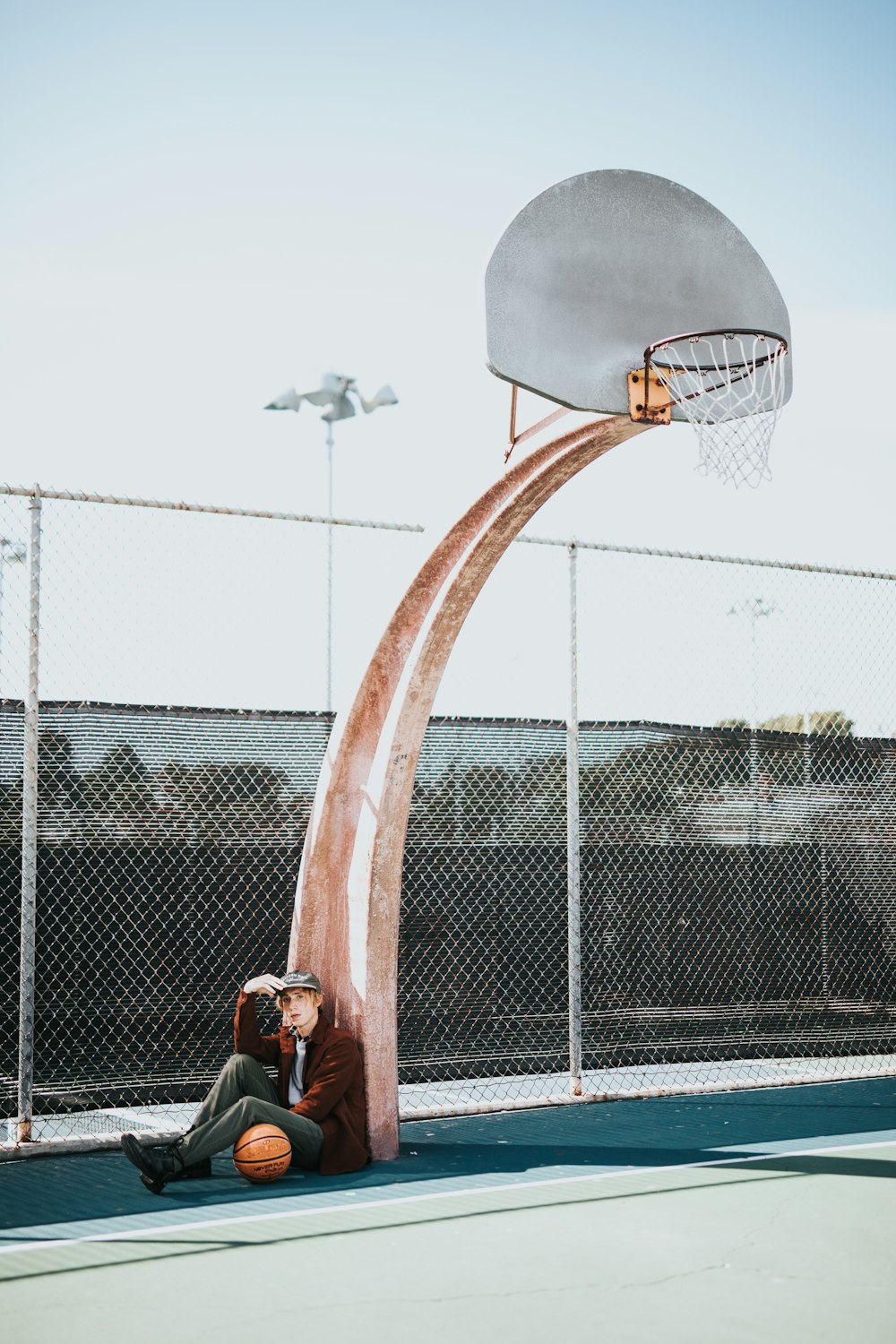 man sitting beside basketball hoop